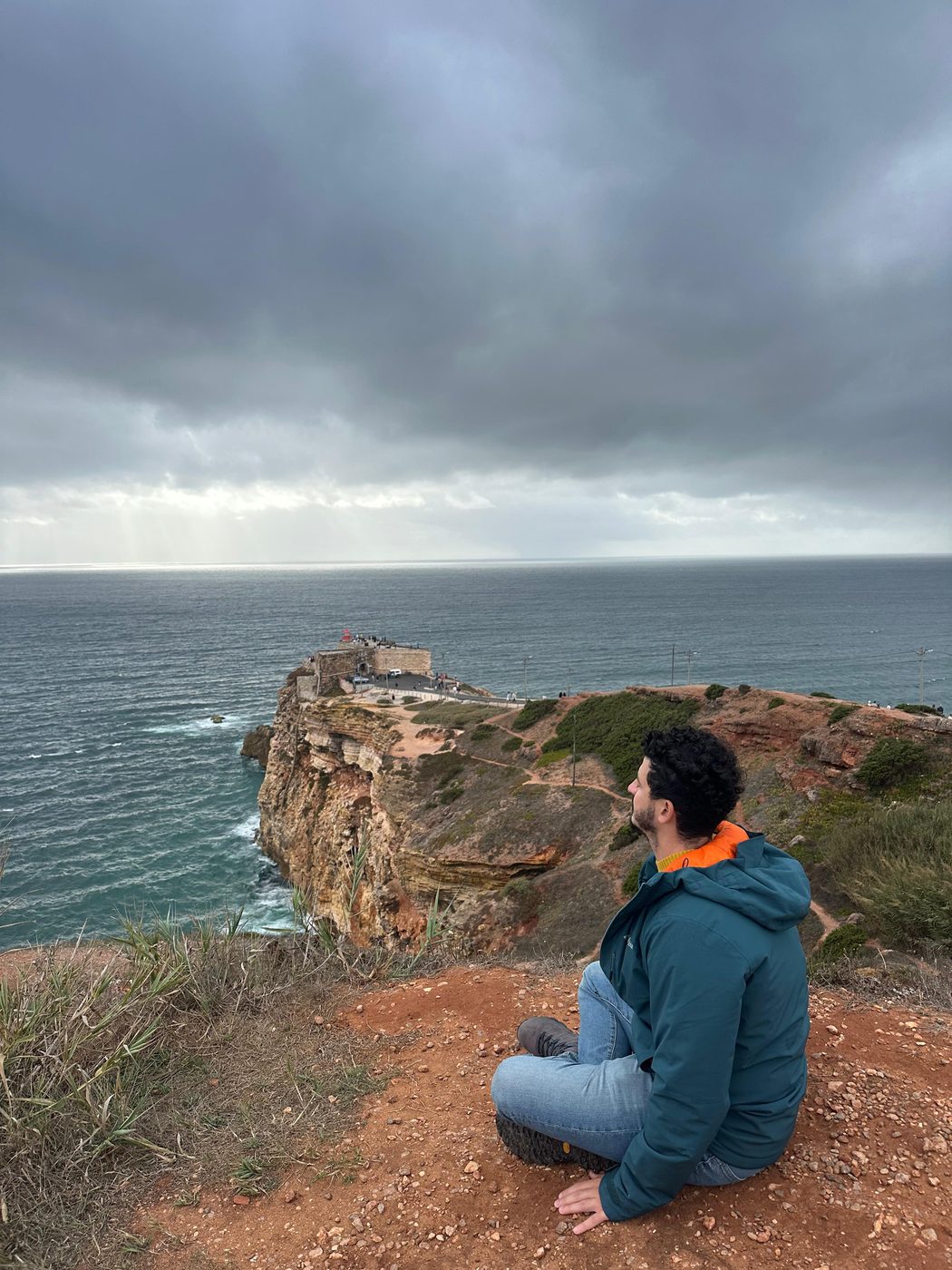 Altauri sitting in quiet meditation before the sea, Nazaré, Portugal